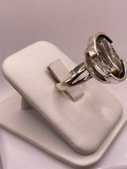 Detalle lateral del anillo mostrando el engaste a mano y la banda de plata pulida espejo