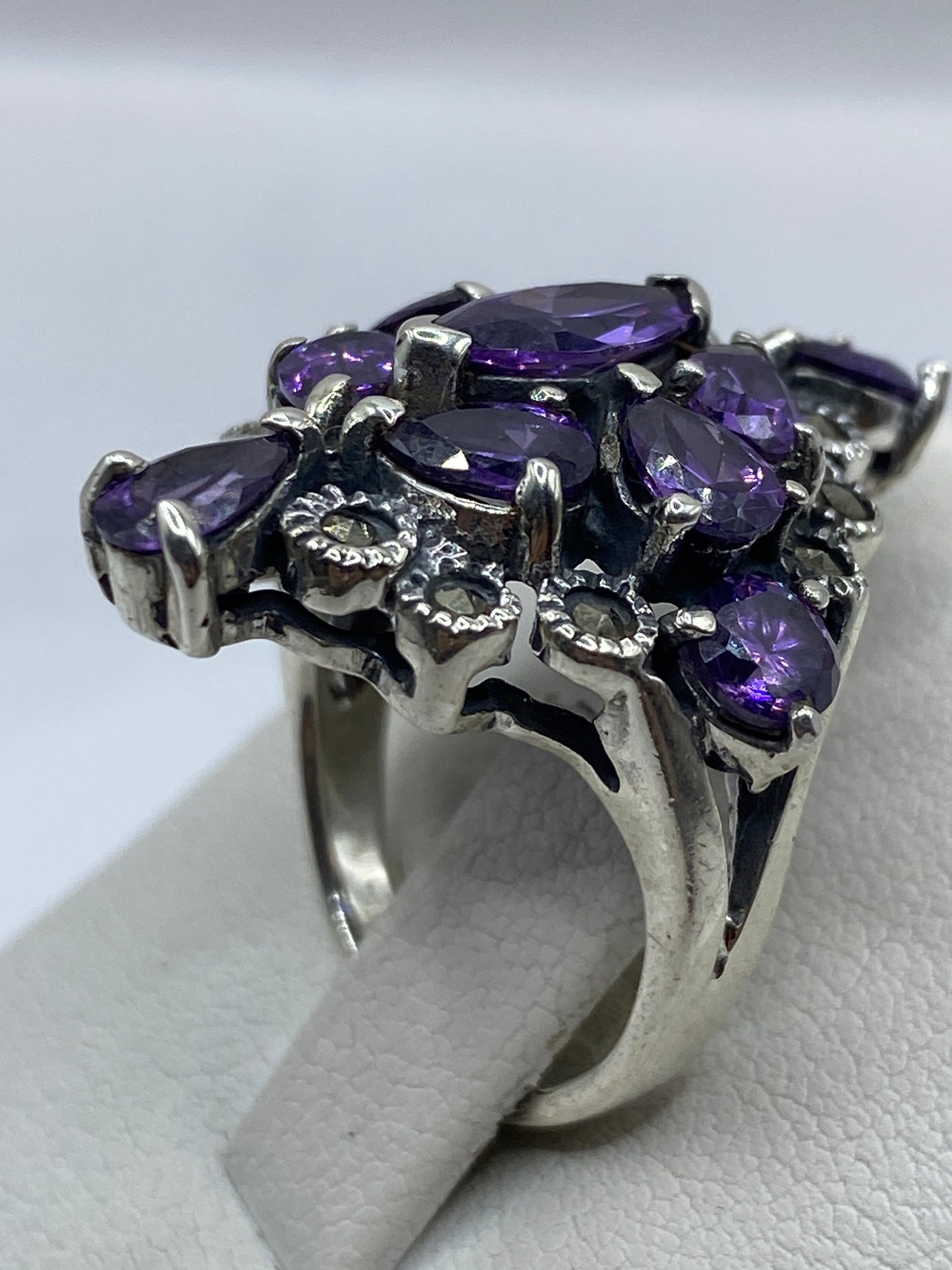 Anillo coctel de plata con circonias púrpuras facetadas en la mano de una mujer