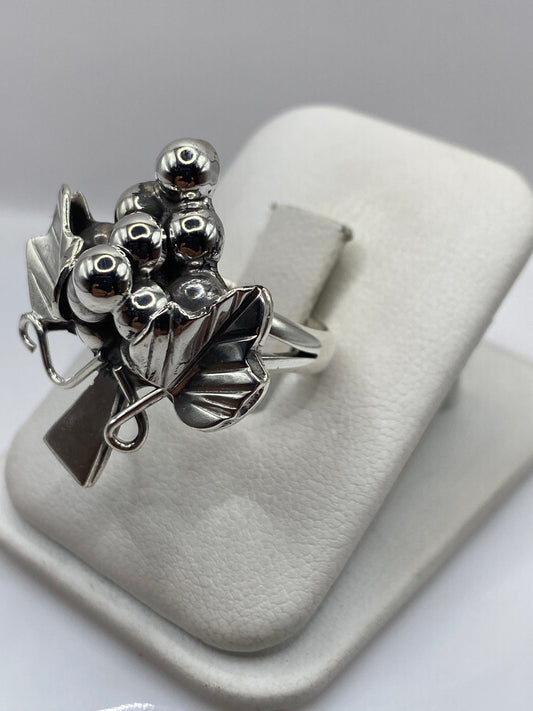 Anillo racimo en dedo, mostrando el diseño floral con esferas pulidas a espejo