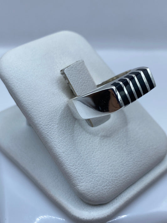 Anillo unisex de ónix y plata pulido a mano, vista lateral sobre dedo, luz natural