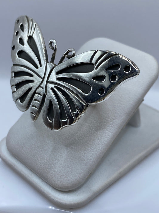 Detalle lateral del anillo mariposa mostrando las alas en relieve sobre dedo