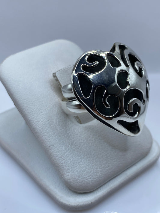 Vista frontal del anillo ajustable corazón calado sobre dedo de mujer