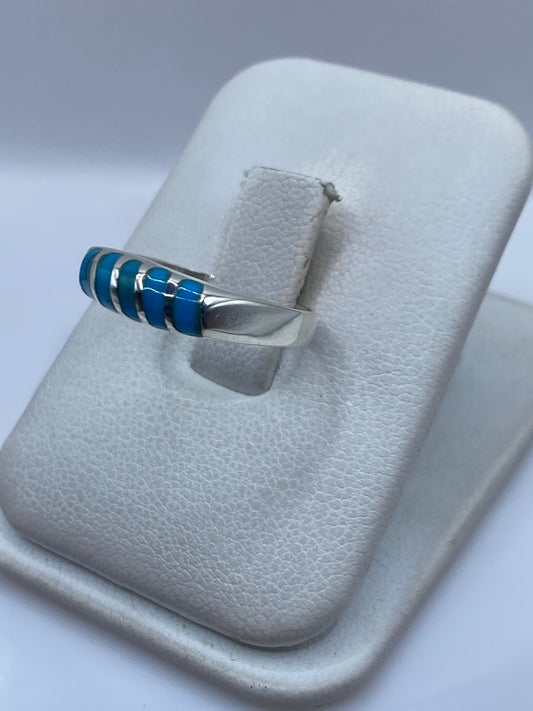 Detalle del anillo mostrando el engaste a mano de la turquesa entre franjas de plata