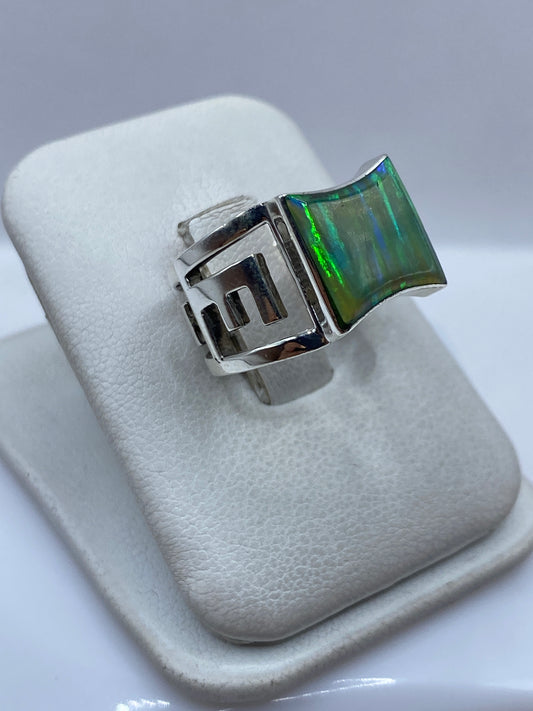 Vista frontal del anillo de ópalo de fuego con efecto iridiscente en verde y azul