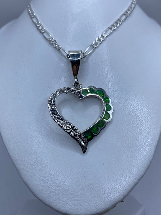 Detalle de la incrustación de ópalo de fuego con tonalidad verde luminosa en el dije corazón