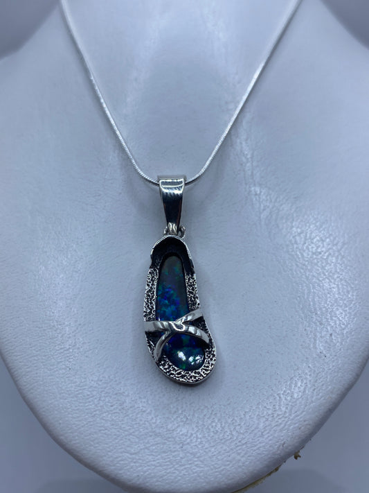 Dije de plata .950 con ópalo de fuego azul sobre pecho blanco, mostrando tamaño real de 4.5 cm