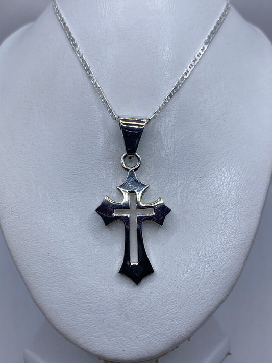Cruz de plata colgando en cadena plateada, mostrando el diseño cruciforme clásico