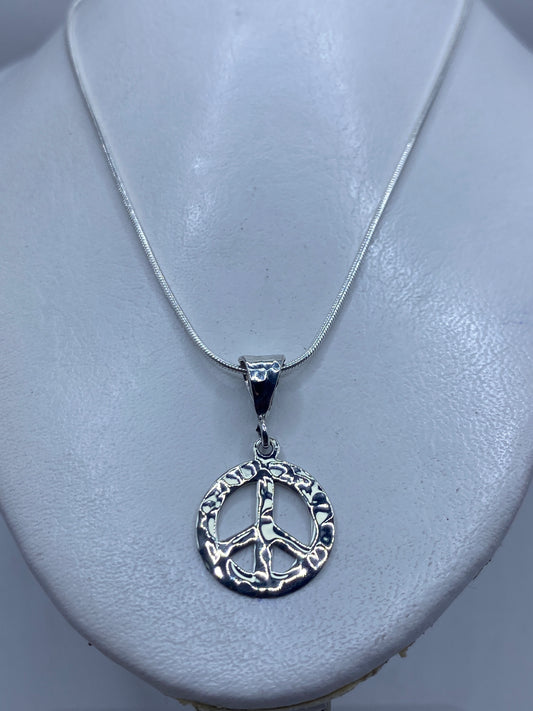 Detalle del símbolo de paz en relieve, repujado a mano en plata .925