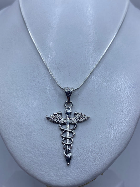 Dije Caduceo sobre pecho, vista de cómo se ve puesto — 4.4 cm de largo