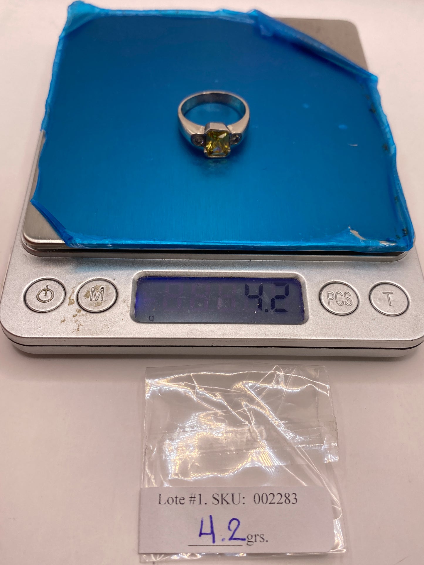 Anillo de circonia amarilla sobre fondo azul mostrando peso de 4.2 gramos