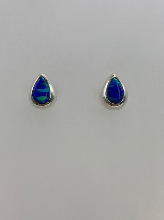 Detalle lateral de aretes de plata con ópalo azul, mostrando el engaste delicado