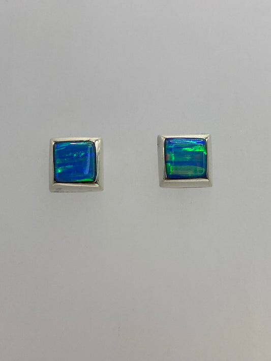 Vista frontal de los aretes mostrando el juego de luz del ópalo en ambas piedras