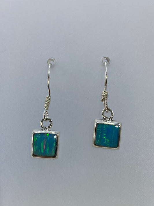 Aretes de plata con ópalo de fuego mostrando los tonos naranjas, rojos y verdes de la piedra