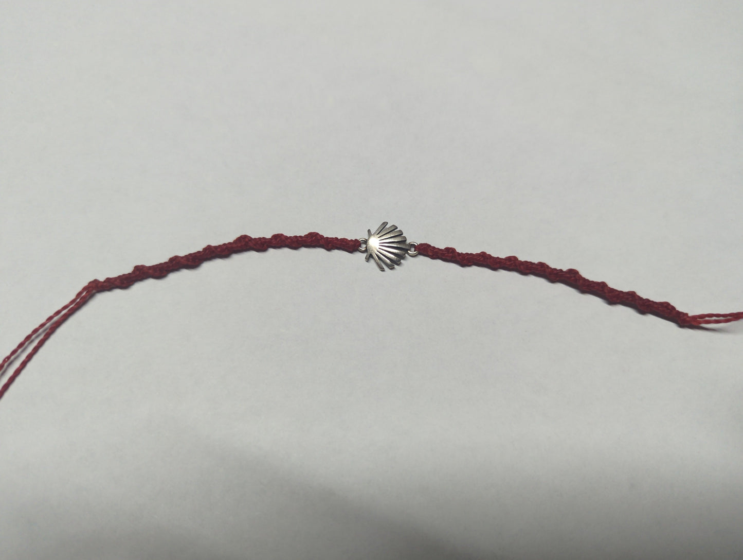 Pulsera trenzada de cordón burdeos con dije de concha en plata .925