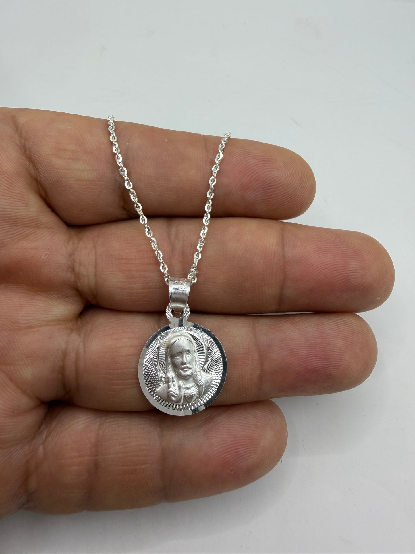 Medalla de San Judas en plata .925 sostenida en la mano, mostrando la definición del rostro grabado