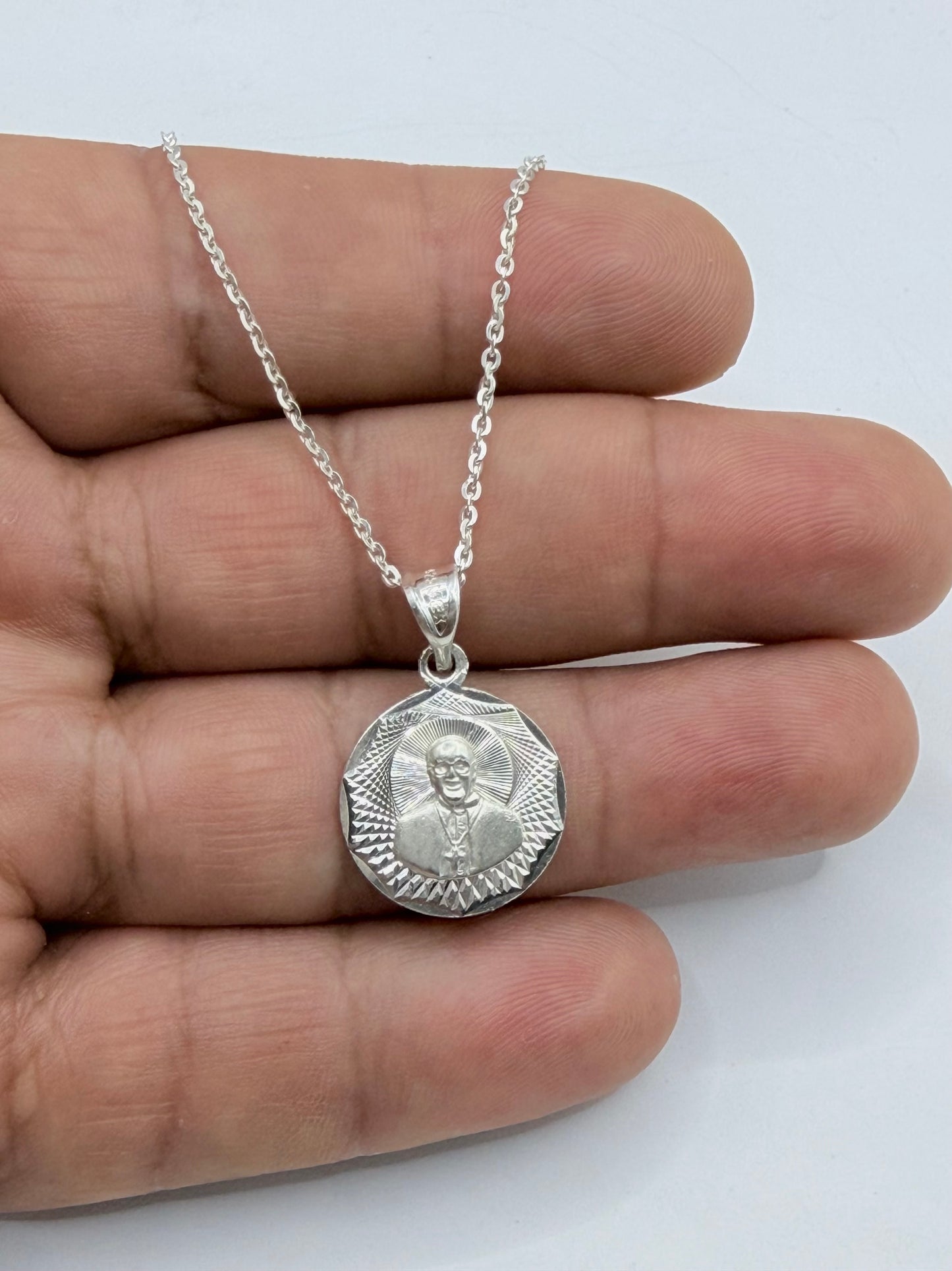 Medalla religiosa de plata .925 en mano, mostrando relieve y textura