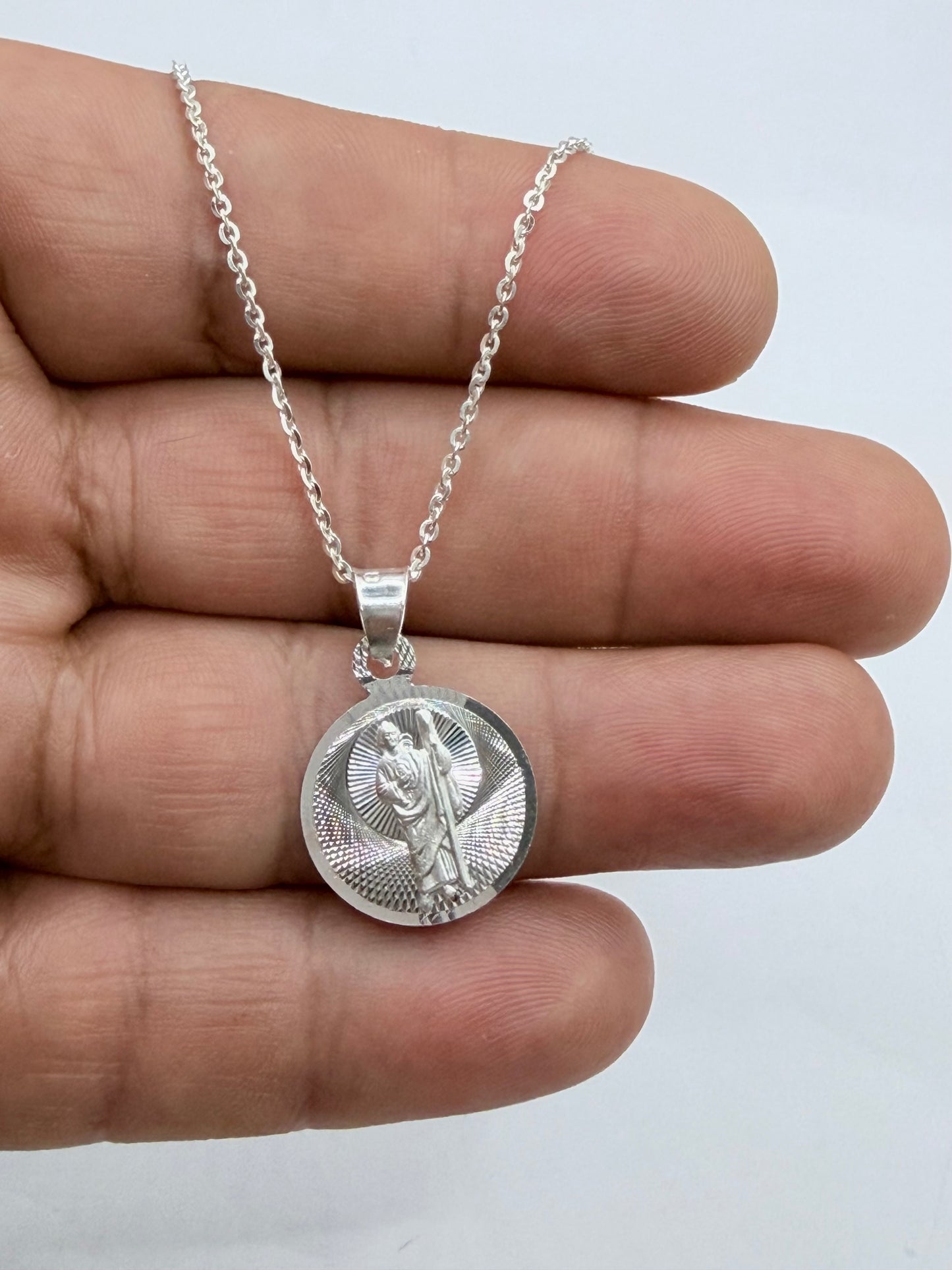 Medalla y cadena vistas de cerca mostrando el acabado diamantado y el brillo de la plata
