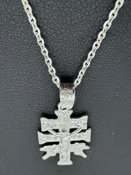 Detalle del dije Cruz de Carabaca en fundición de plata pura, mostrando relieves religiosos