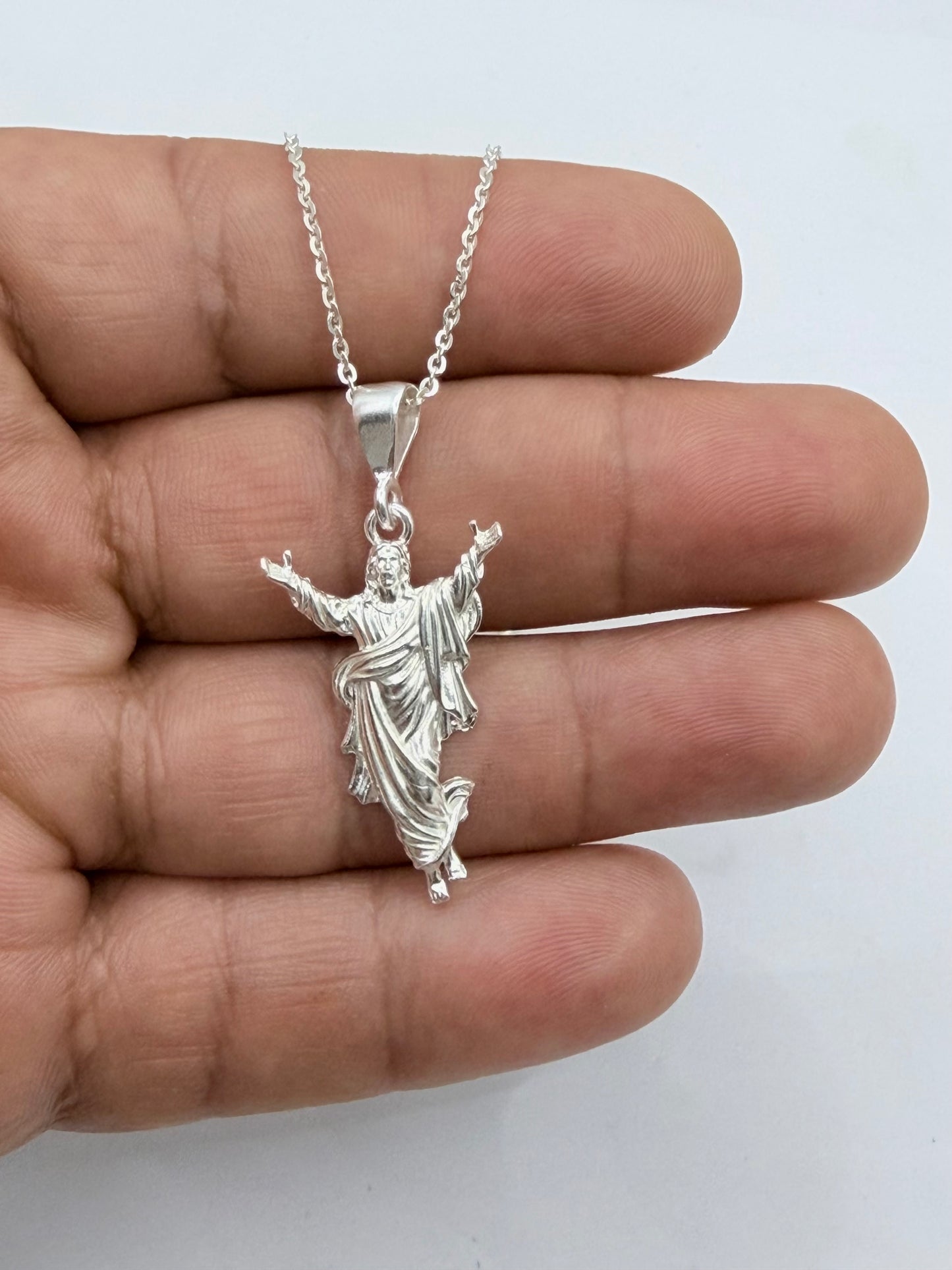 Collar Cristo en plata .925 posado sobre mano, mostrando tamaño real del dije de 4 cm de alto