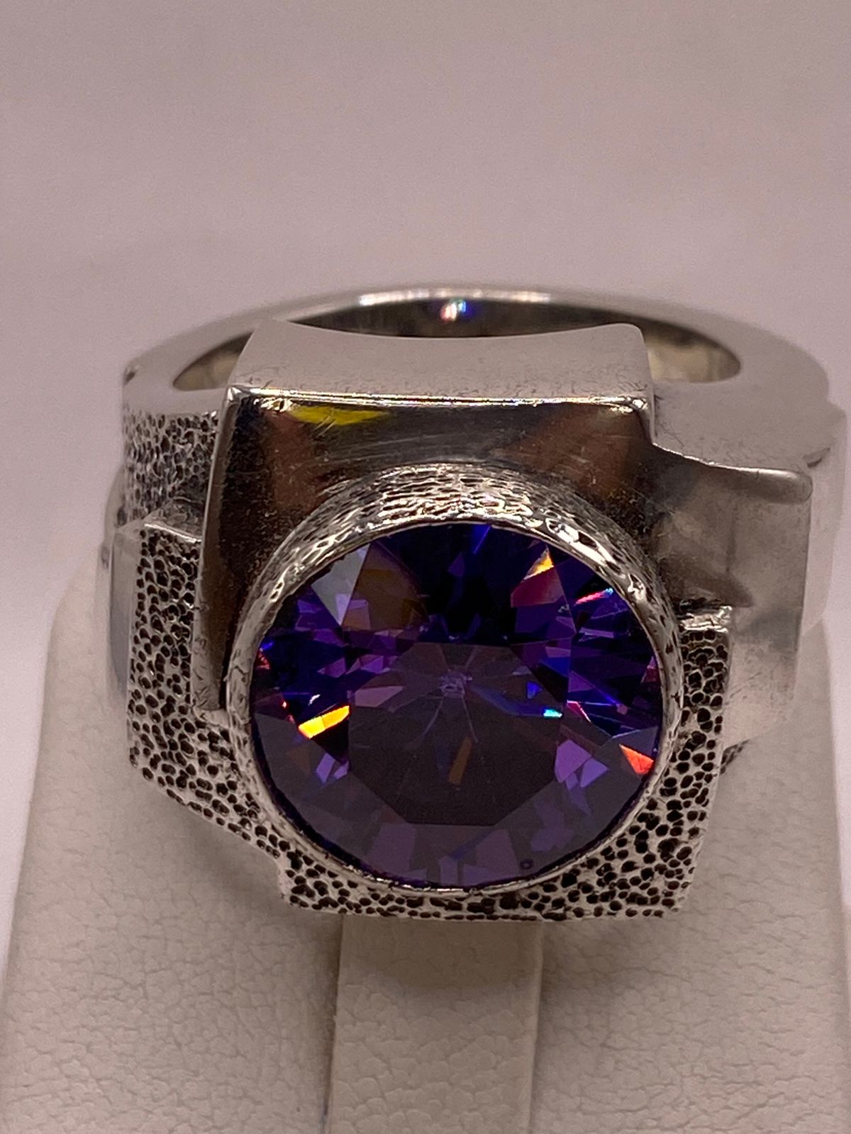 Detalle de circonia tornasol facetada en montura elevada de plata .925 — destellos violeta y azul, anillo artesanal Taxco

