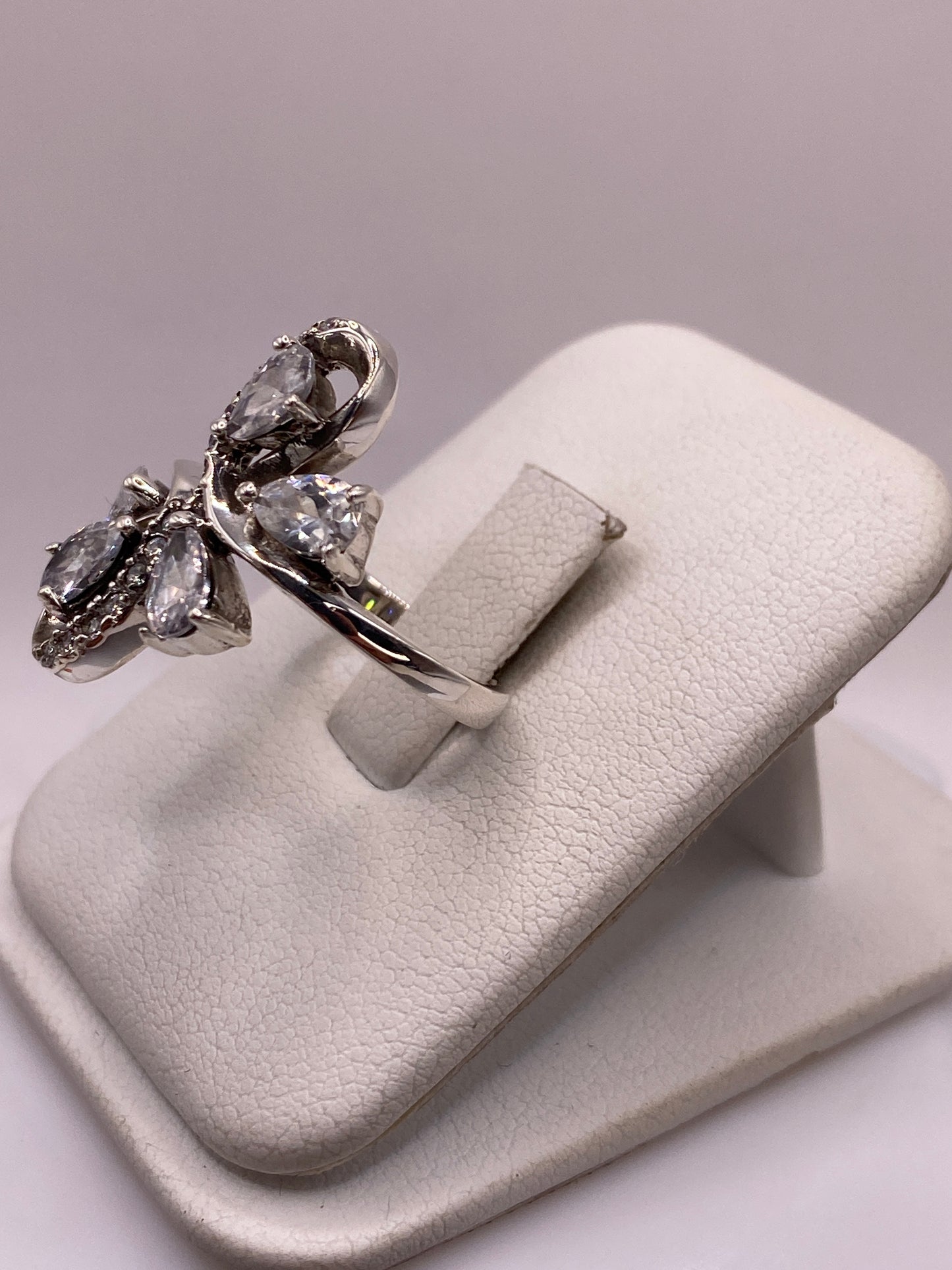 Anillo de plata mariposa con brillo de diamante en la mano de una mujer, mostrando el diseño coctel