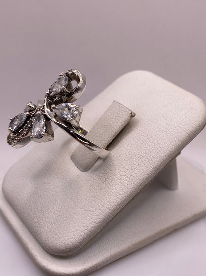 Anillo de plata mariposa con brillo de diamante en la mano de una mujer, mostrando el diseño coctel