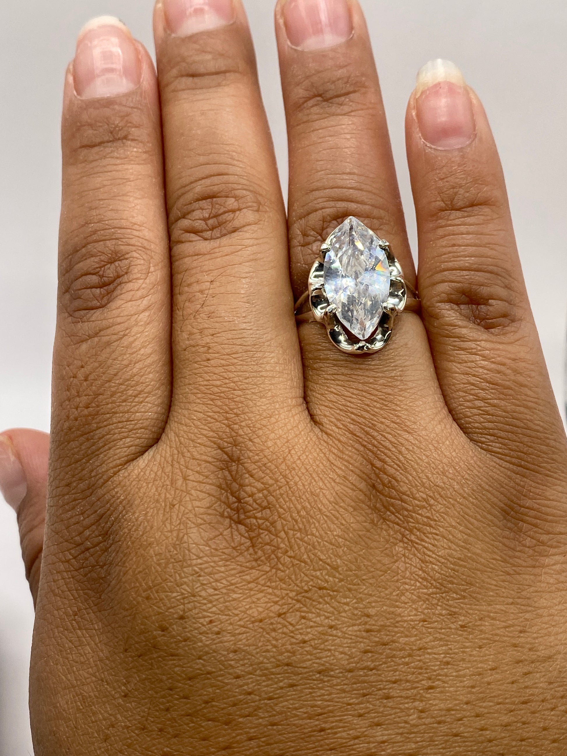 Anillo solitario marqués en la mano mostrando el sello .925 MEXICO