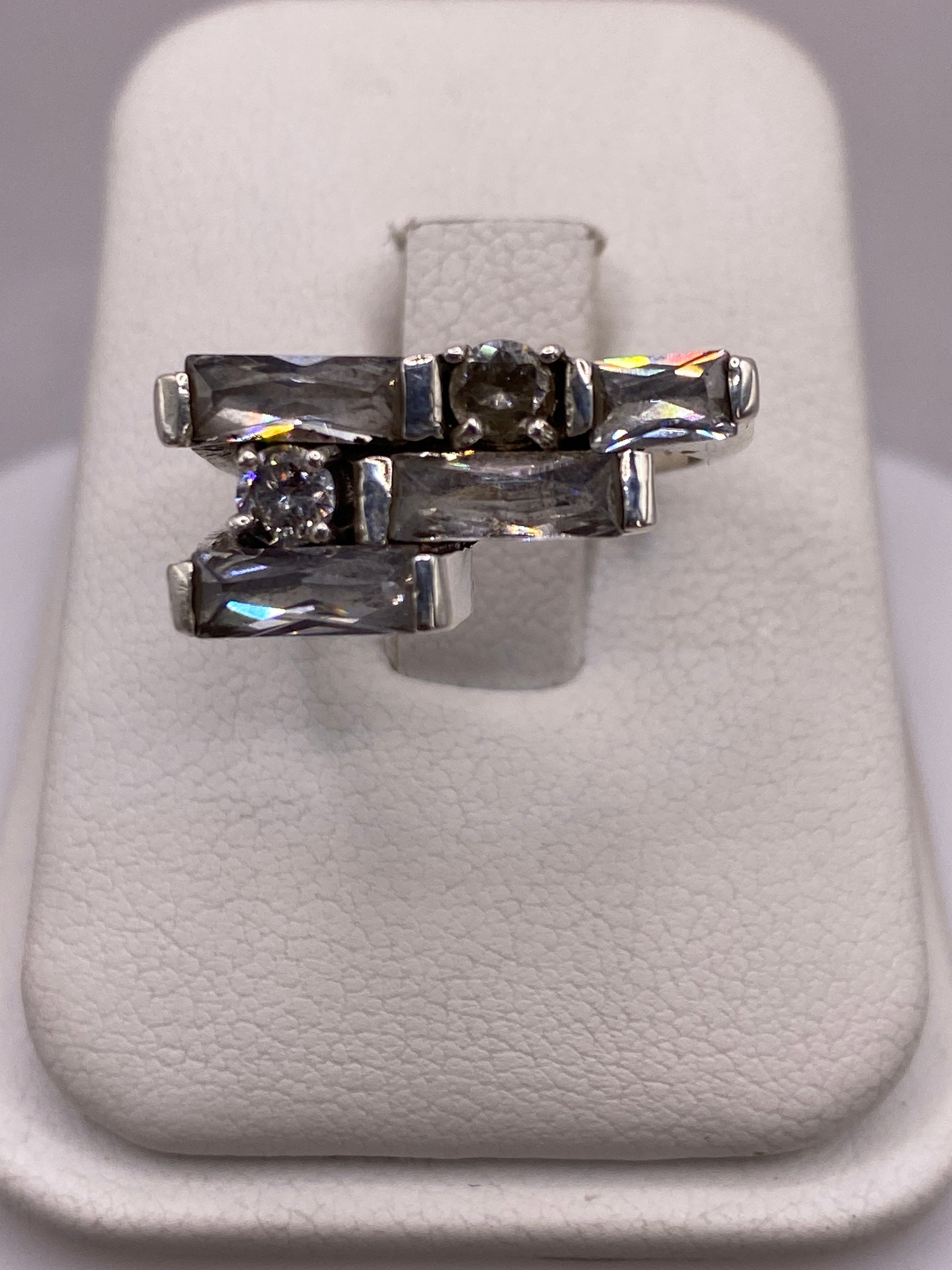 Anillo de plata arquitectónico con circonias blancas y grises, vista superior sobre fondo blanco