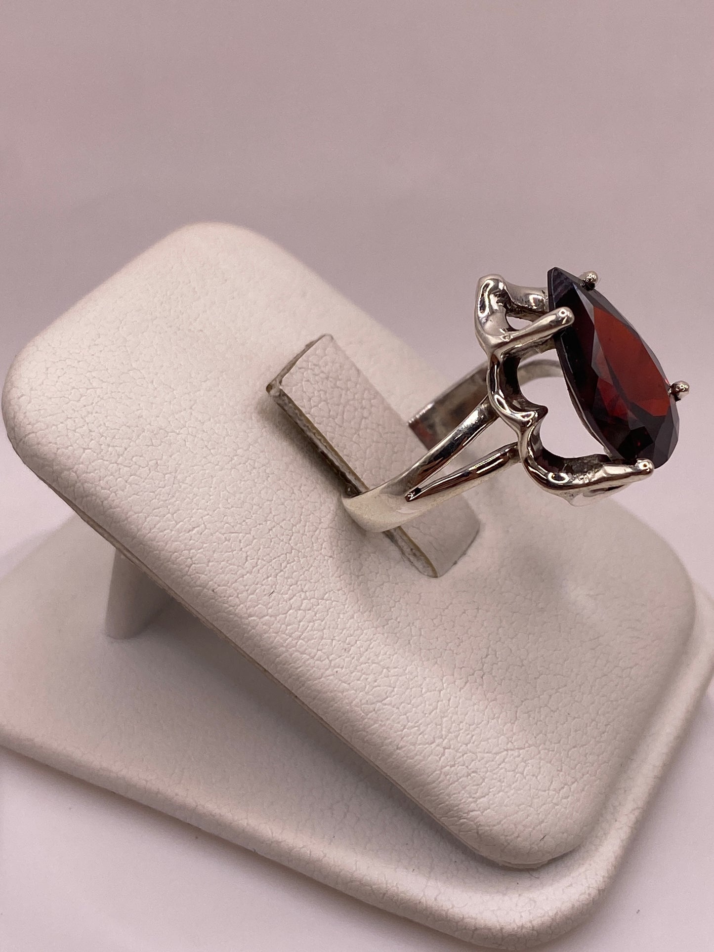 Vista lateral del anillo solitario plata con circonia roja granate mostrando hombros esculpidos y banda dividida