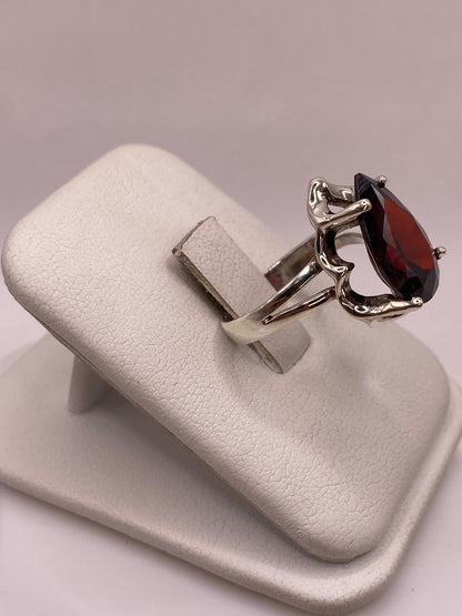Vista lateral del anillo solitario plata con circonia roja granate mostrando hombros esculpidos y banda dividida