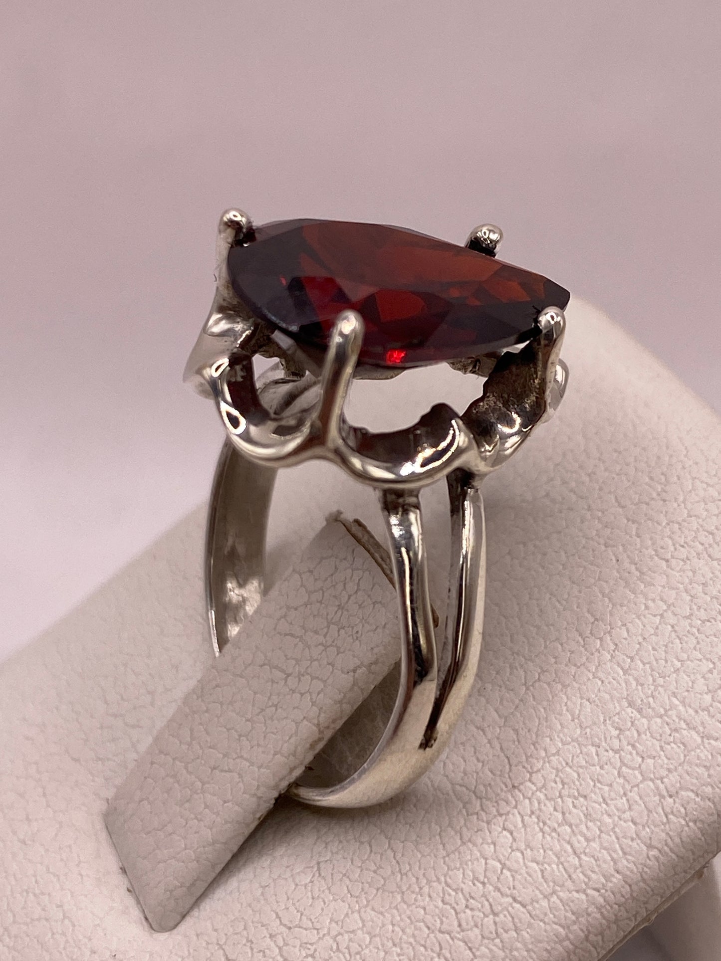 Anillo de plata con circonia roja corte pera puesto en la mano de una mujer, talla 7