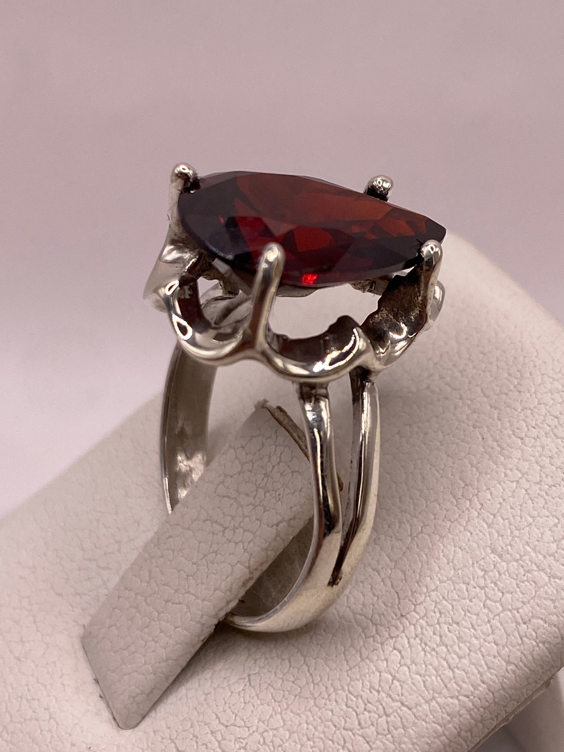 Anillo de plata con circonia roja corte pera puesto en la mano de una mujer, talla 7