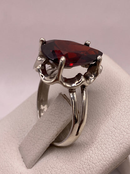 Anillo de plata con circonia roja corte pera puesto en la mano de una mujer, talla 7