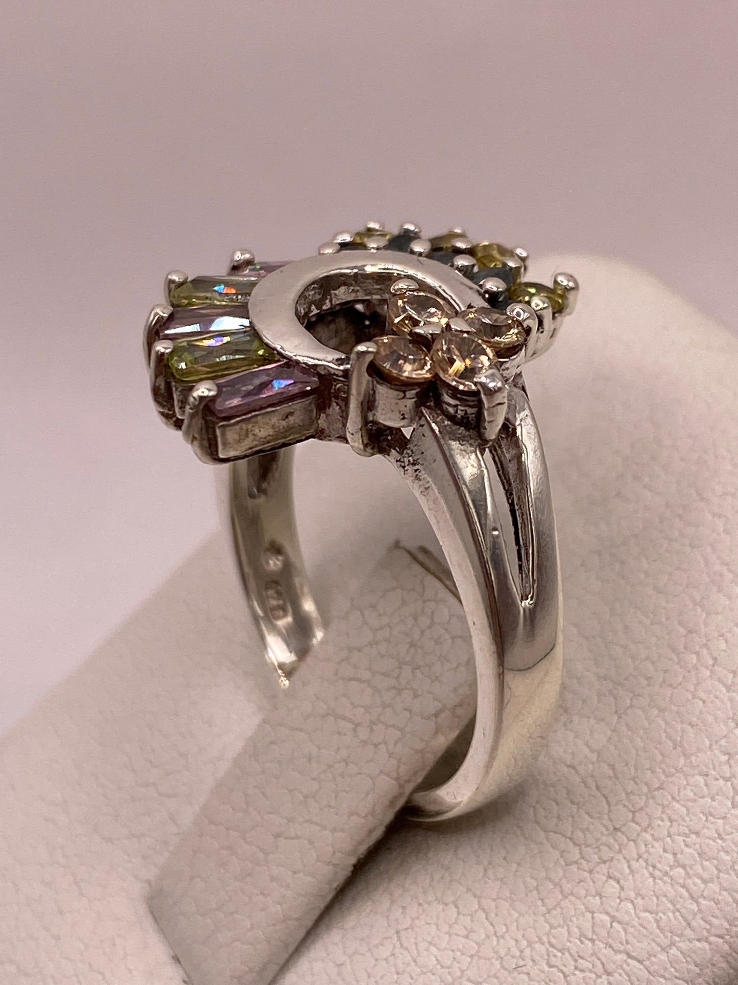 Detalle del engaste en garras del anillo de plata luna creciente con baguettes lila y verde y sello 925 en la banda