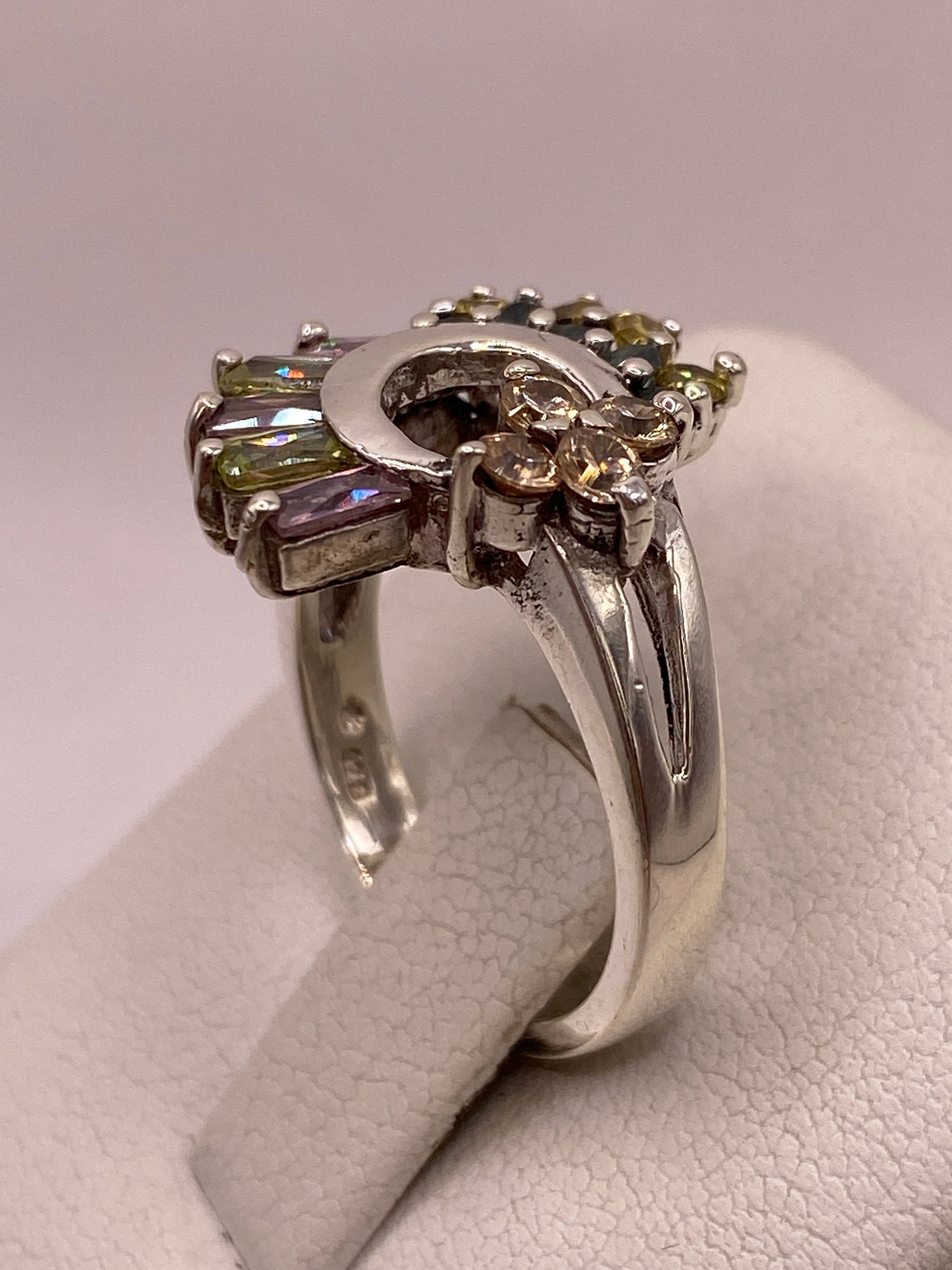 Detalle del engaste en garras del anillo de plata luna creciente con baguettes lila y verde y sello 925 en la banda