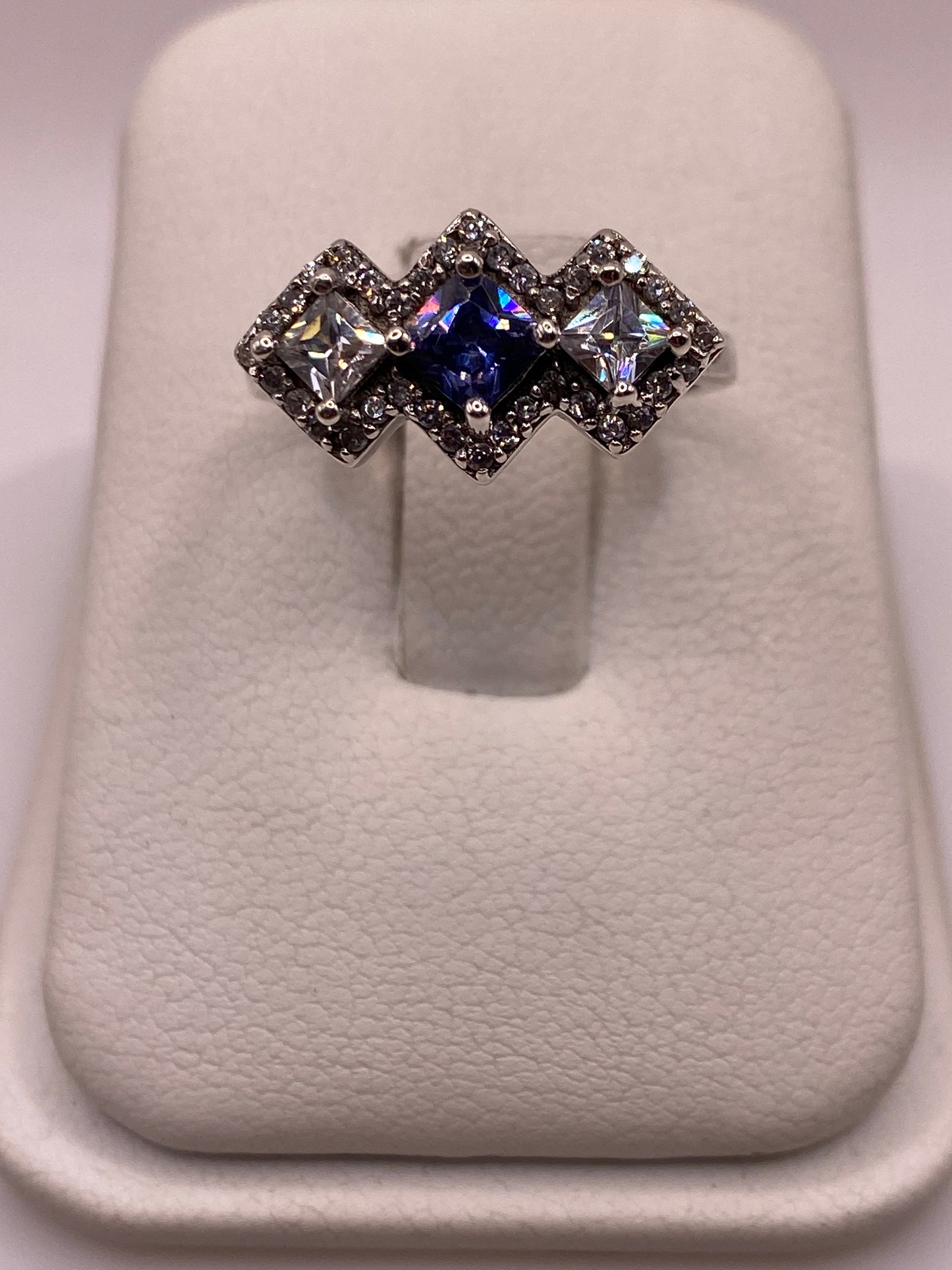 Anillo de plata .925 con tres circonias princess en diagonal —azul centro y blancas— sobre soporte blanco