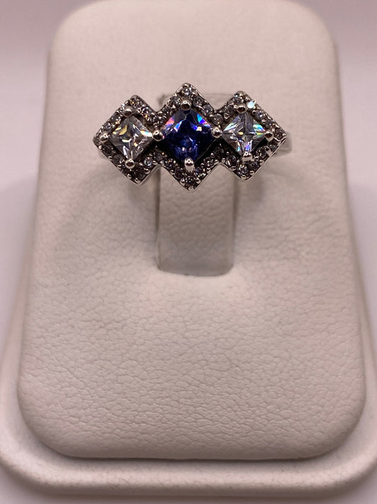Anillo de plata .925 con tres circonias princess en diagonal —azul centro y blancas— sobre soporte blanco