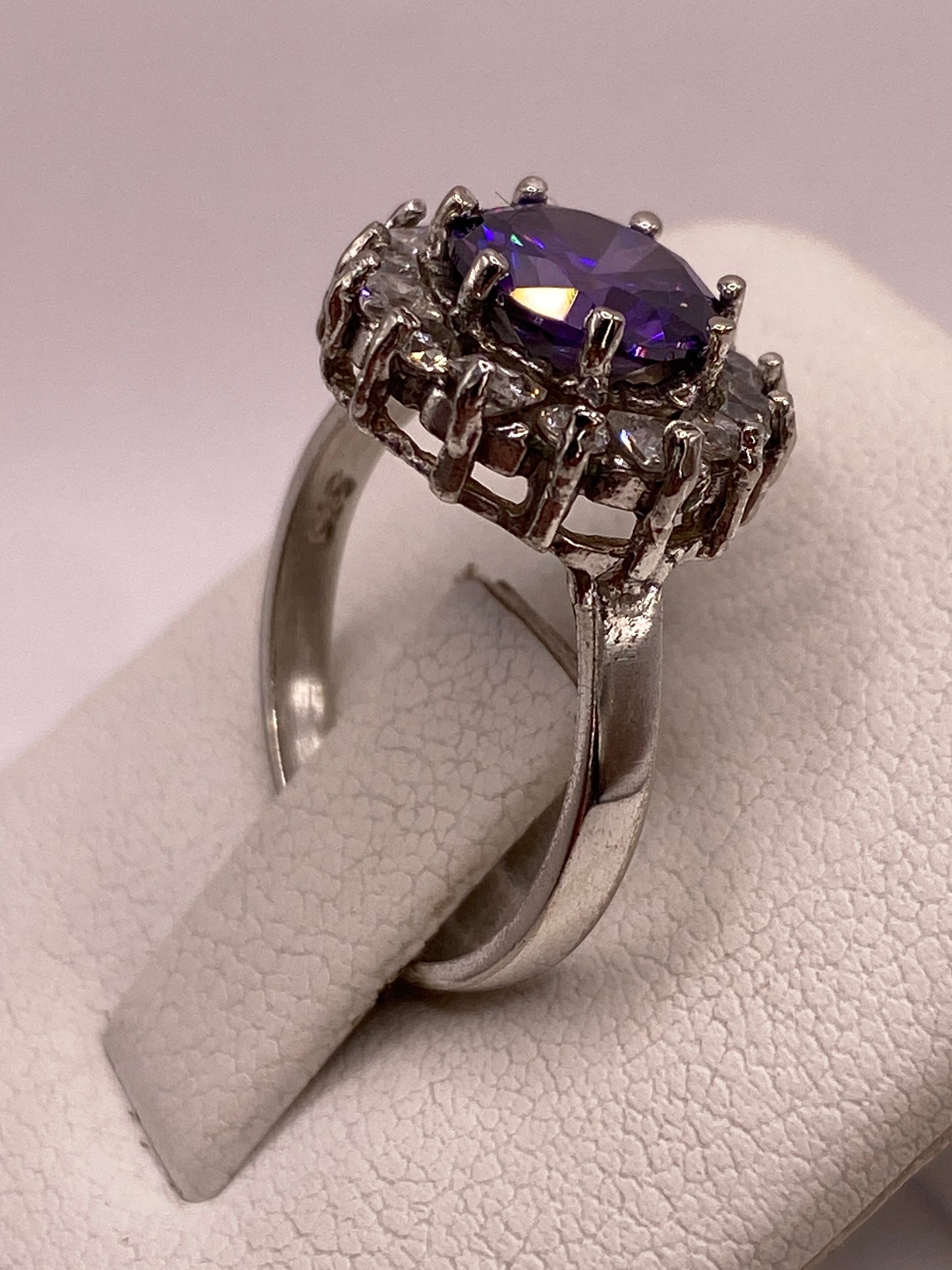 Detalle del frente del anillo: circonia morada redonda rodeada de corona de circonias blancas en plata