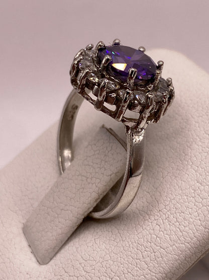 Detalle del frente del anillo: circonia morada redonda rodeada de corona de circonias blancas en plata