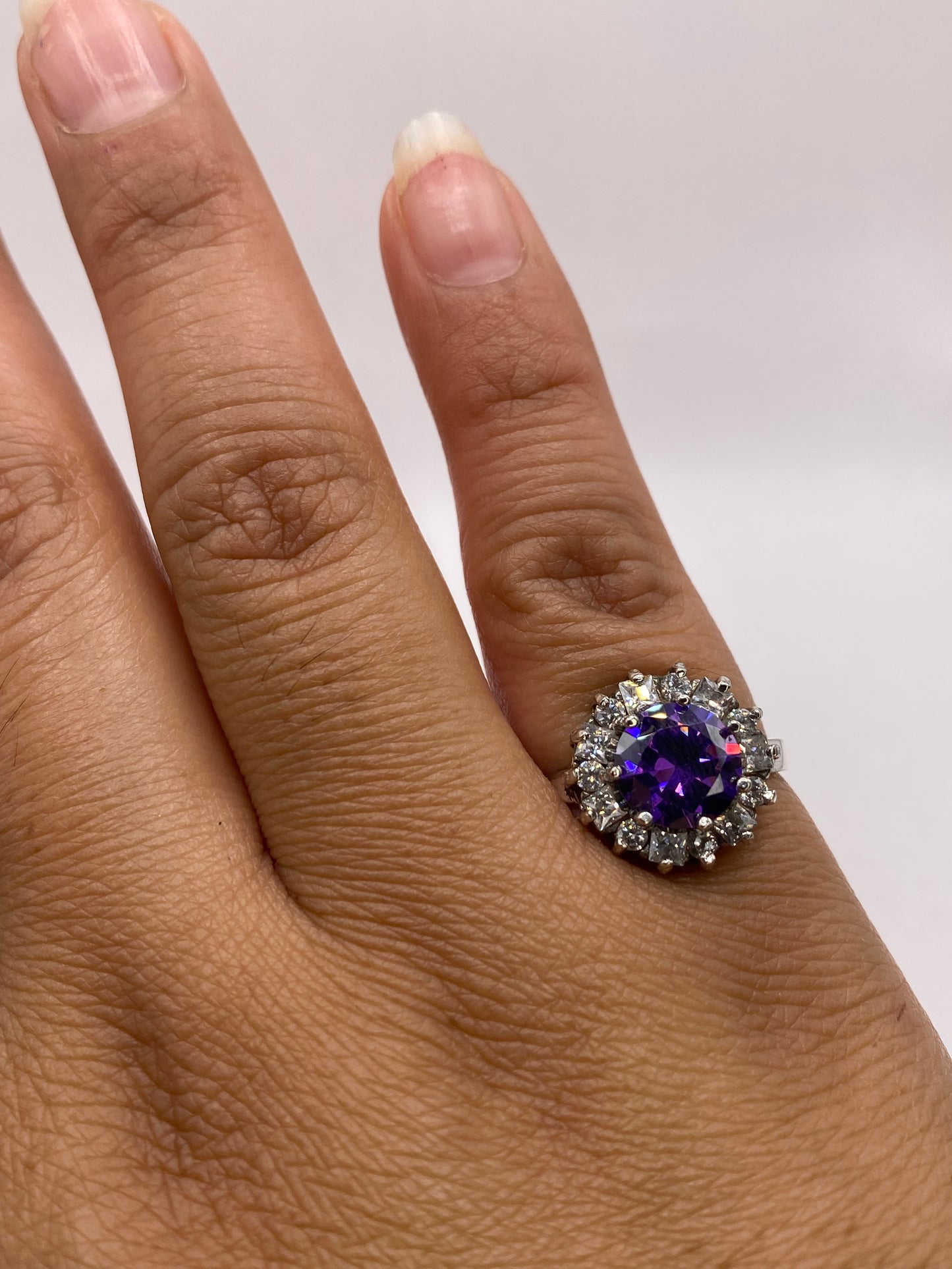 Anillo halo de circonia morada en plata .925 puesto en la mano de una mujer, talla 6