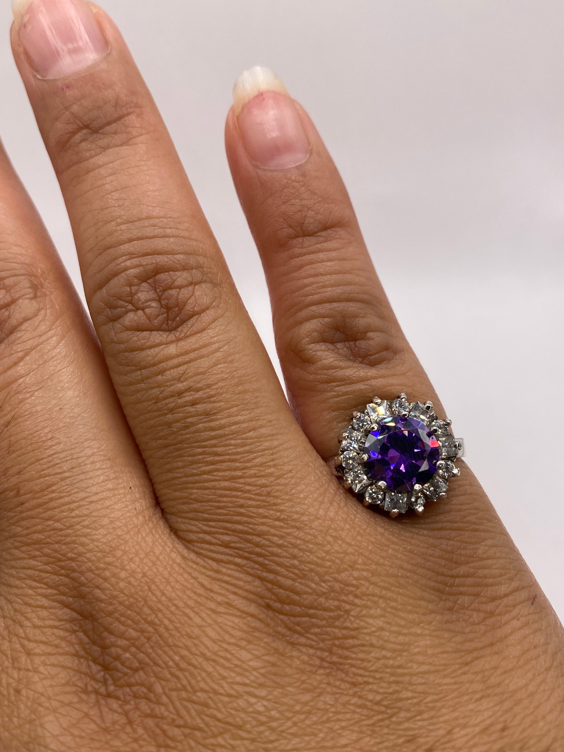 Anillo halo de circonia morada en plata .925 puesto en la mano de una mujer, talla 6