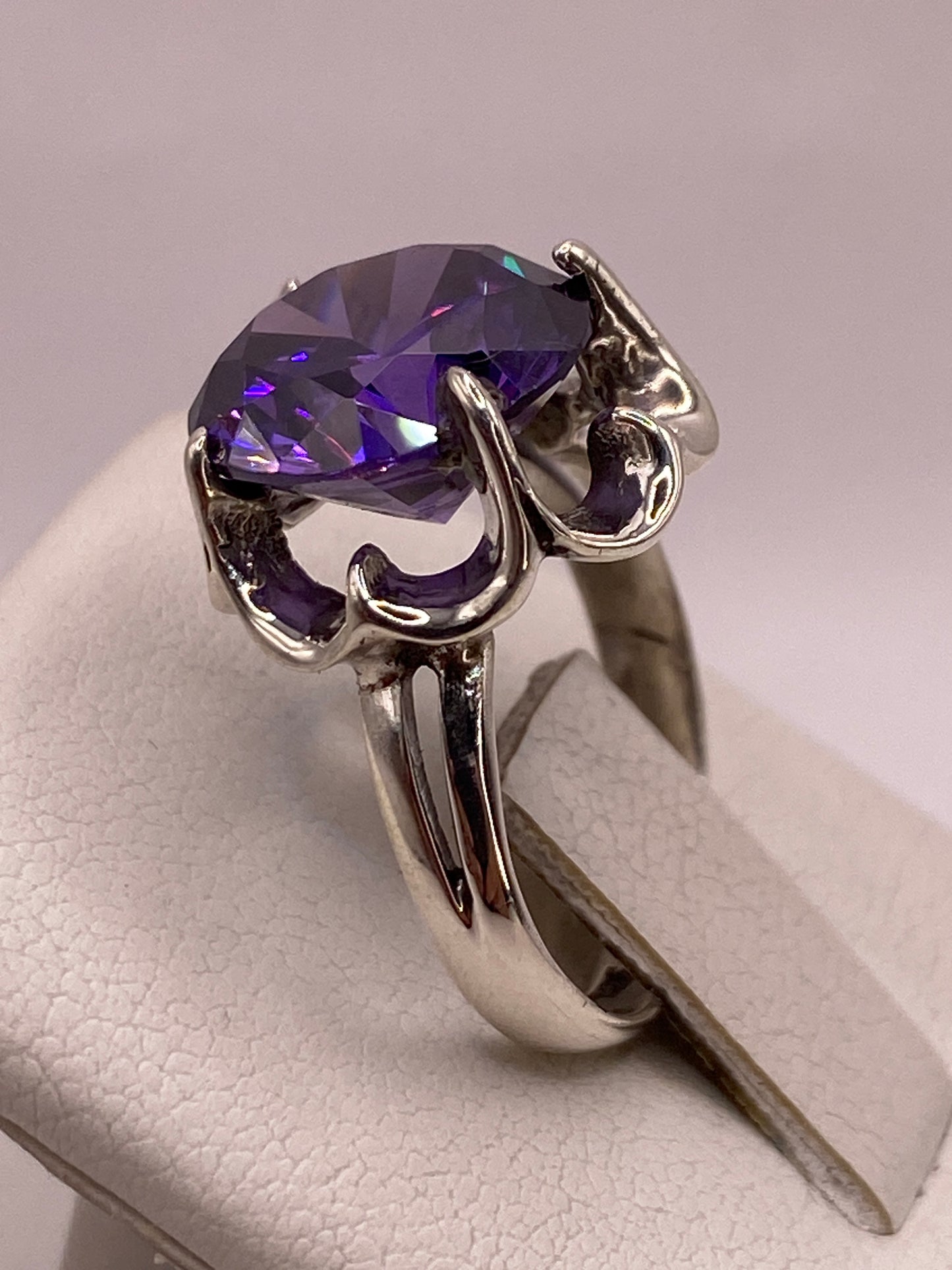 Detalle del engaste de garras con volutas en plata y circonia violeta con destellos multicolor