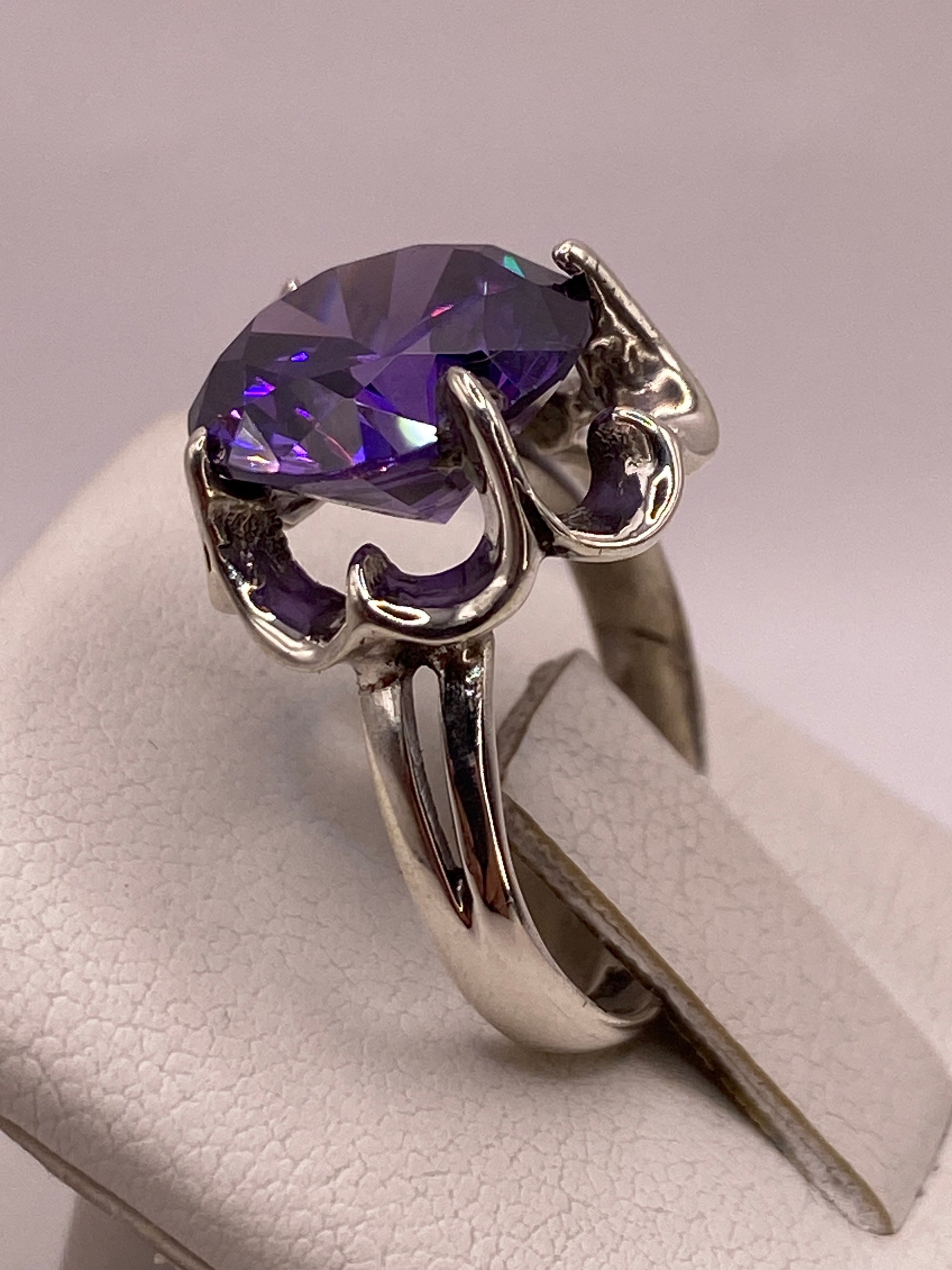 Detalle del engaste de garras con volutas en plata y circonia violeta con destellos multicolor