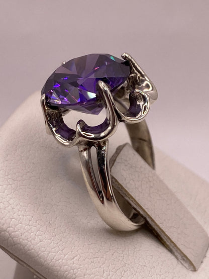 Detalle del engaste de garras con volutas en plata y circonia violeta con destellos multicolor