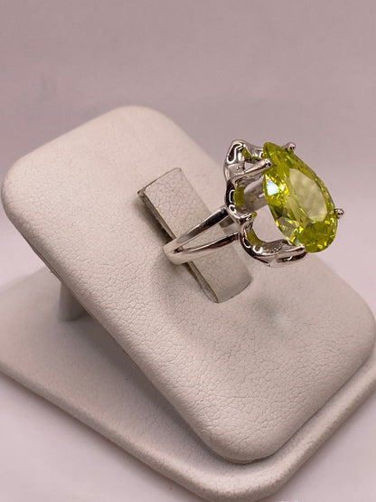 Vista lateral del anillo solitario con circonia verde lima en engaste de garras, banda dividida pulida