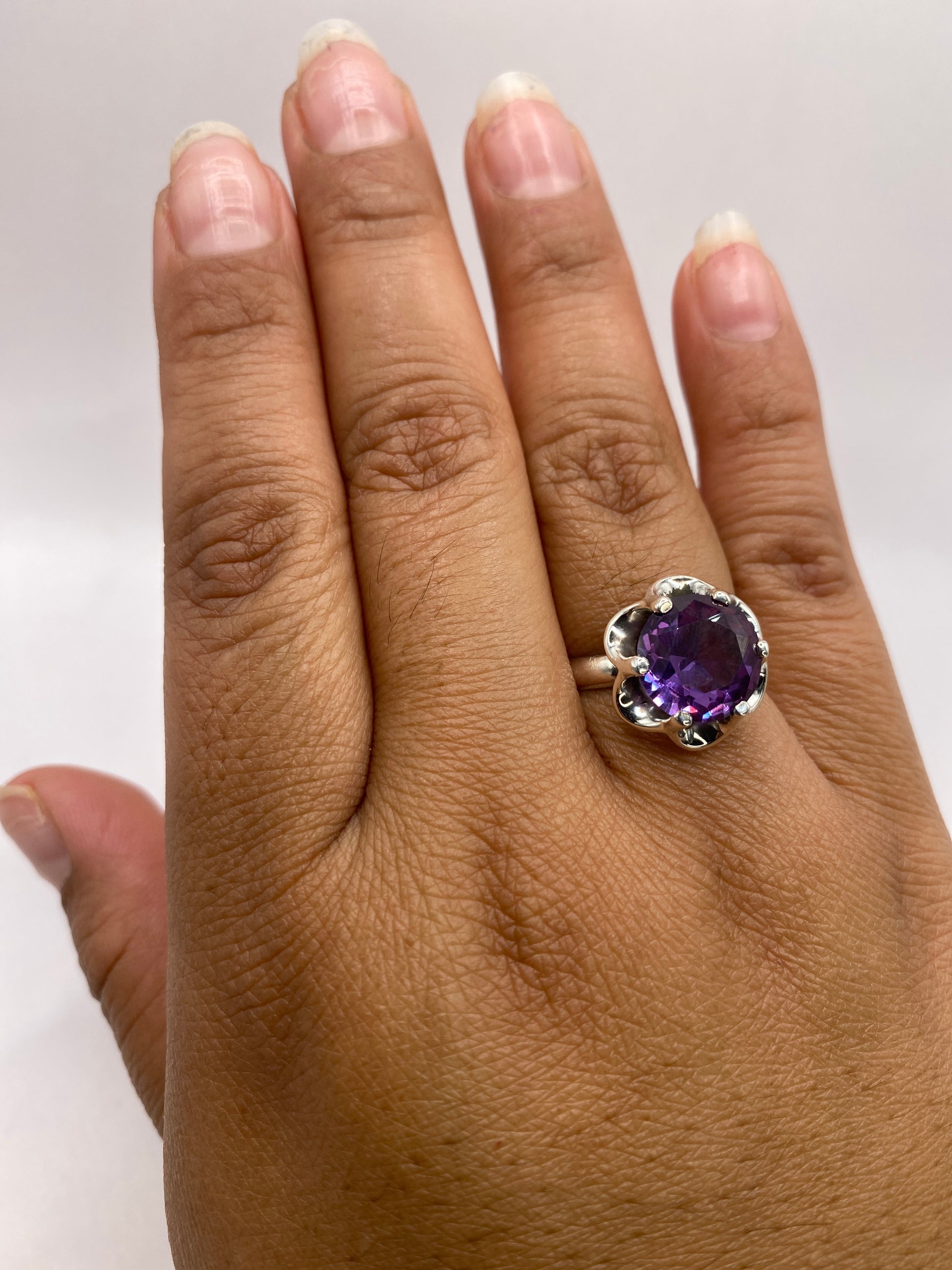 Anillo solitario de circonia morada puesto en la mano de una mujer, talla 7 en plata .925