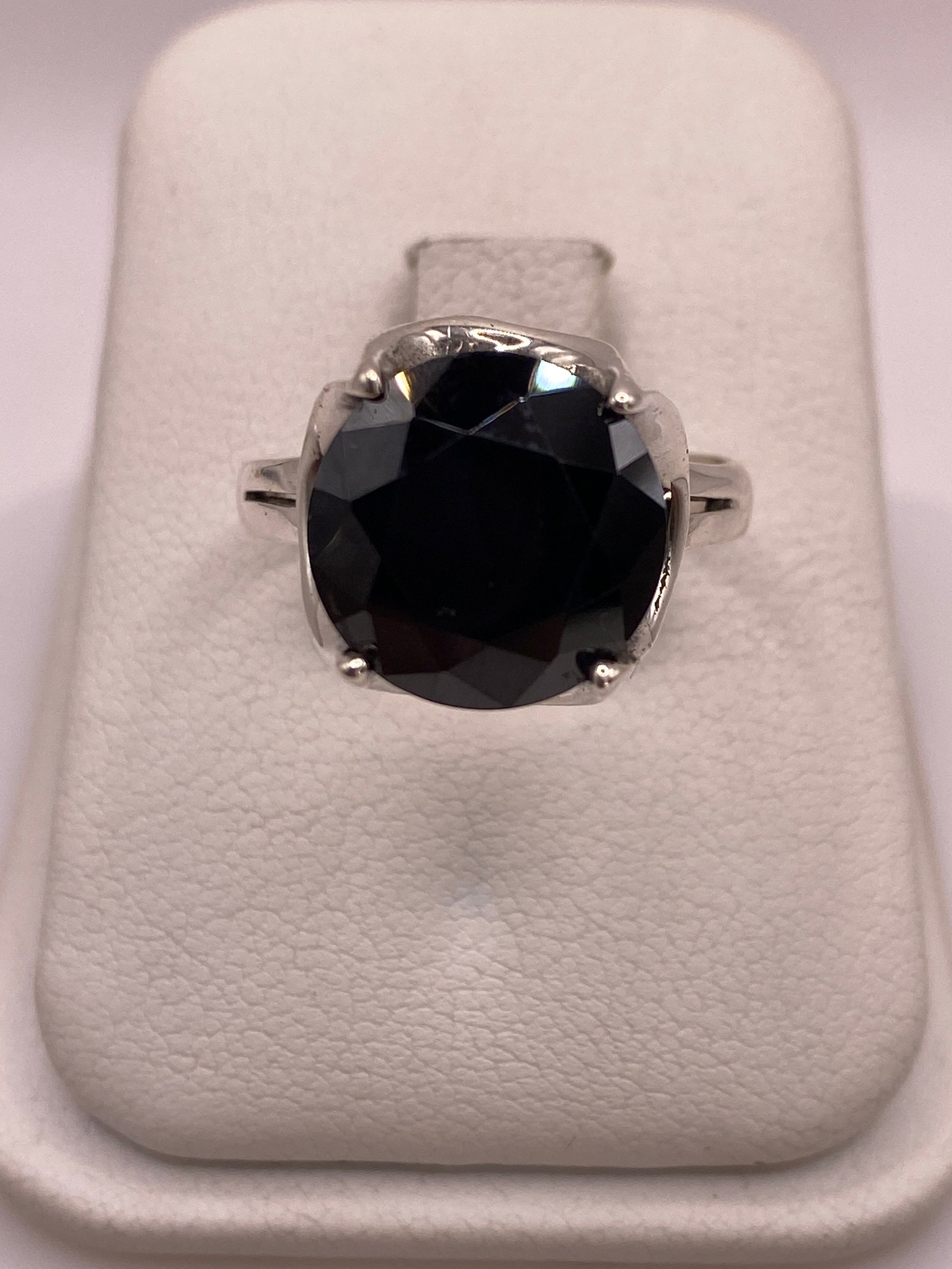 Anillo solitario de plata .925 con circonia negra oval facetada sobre estuche blanco, vista superior