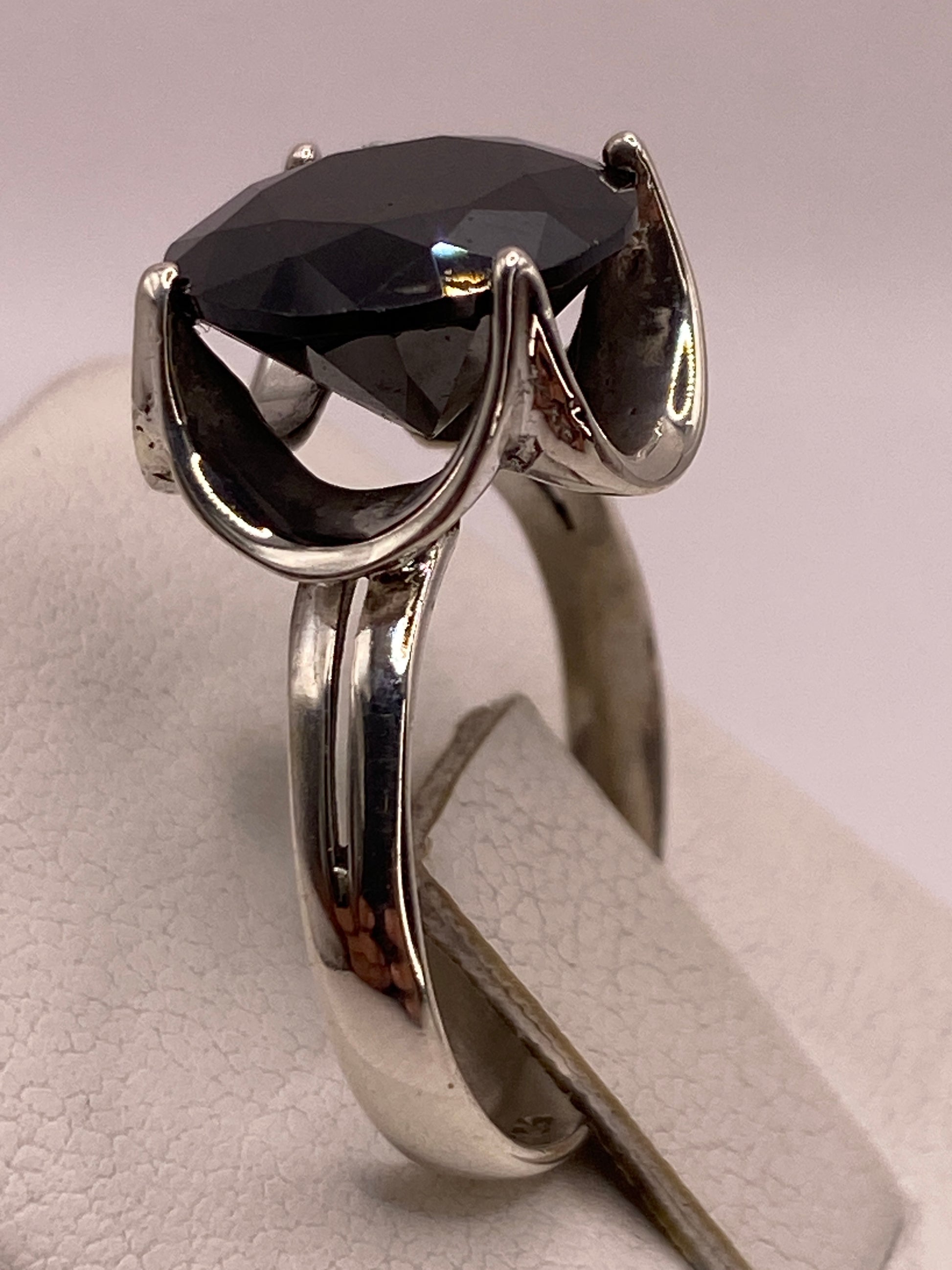 Detalle del engaste en garra y la banda pulida del anillo solitario de plata .925 con sello grabado