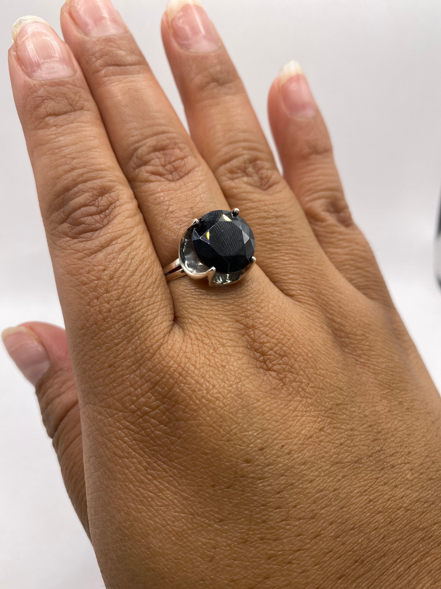 Anillo solitario de circonia negra oval puesto en la mano de una mujer, mostrando escala y presencia en dedo