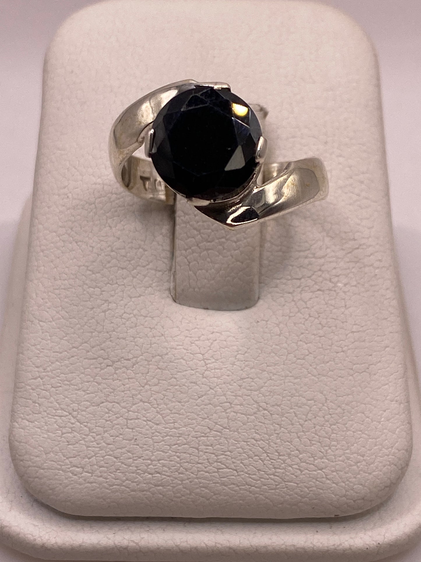 Anillo de plata solitario con circonia negra grande en la mano de una mujer, frente brillante